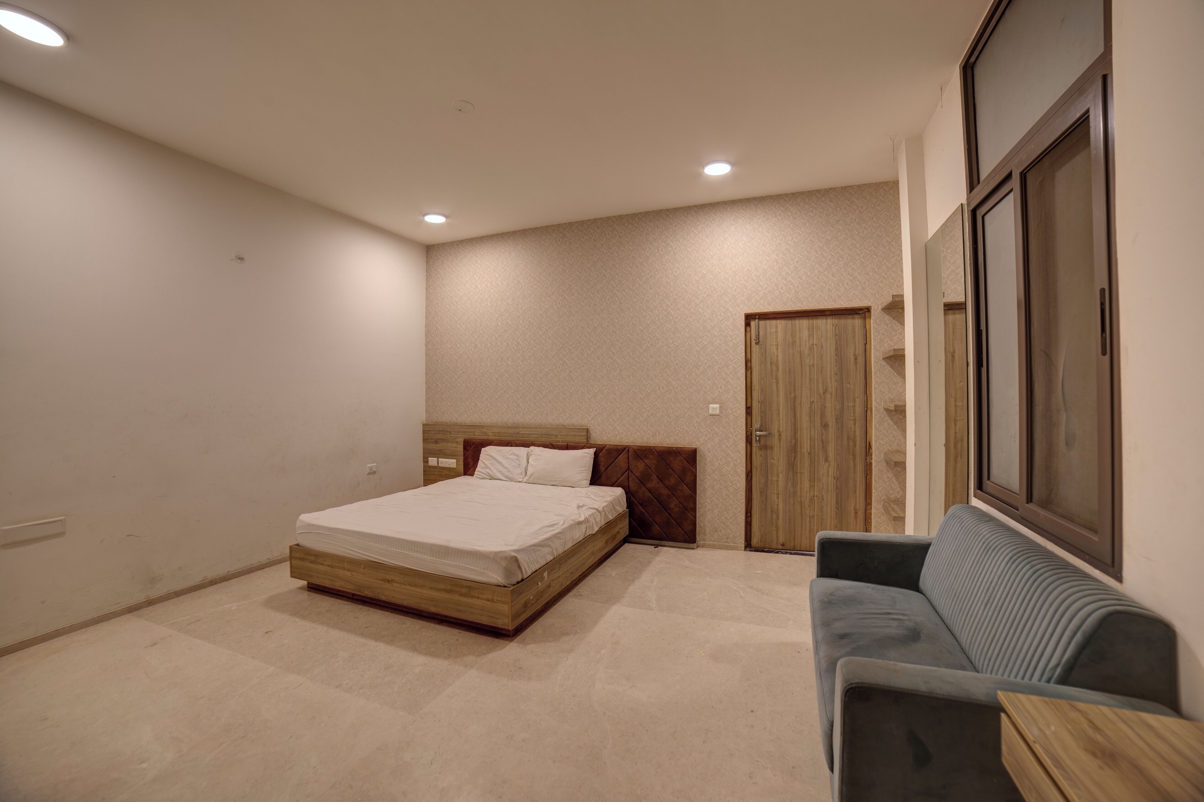 Ein Schlafzimmer mit Bett, Sofa, Holztür und Fenster.