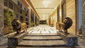 A hotel corridor with marble flooring, two lion statues, and a wooden ceiling. - VRR Hotel's And Convention Centre (Anekal)