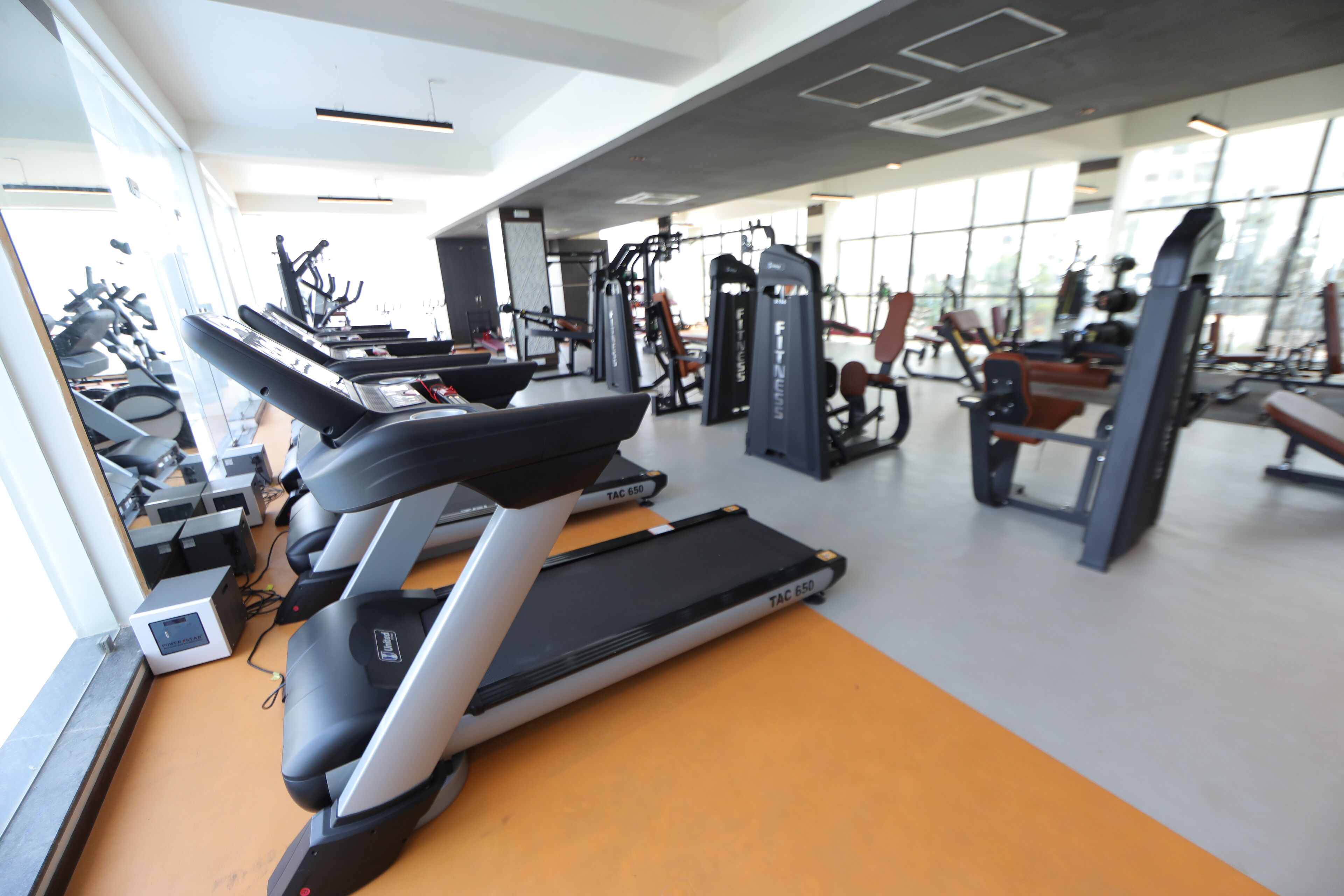 Uma academia com esteiras, máquinas de peso e equipamentos de ginástica.
