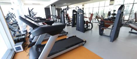 Uma academia com esteiras, máquinas de peso e equipamentos de ginástica.