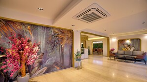 A spacious lobby with a large mural, a reception desk, and a seating area with a sofa and chairs. - VRR Hotel's And Convention Centre (Anekal)