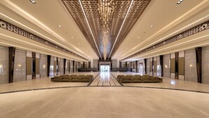 A spacious lobby with a high ceiling, patterned wall designs, and rows of seating. - VRR Hotel's And Convention Centre (Anekal)
