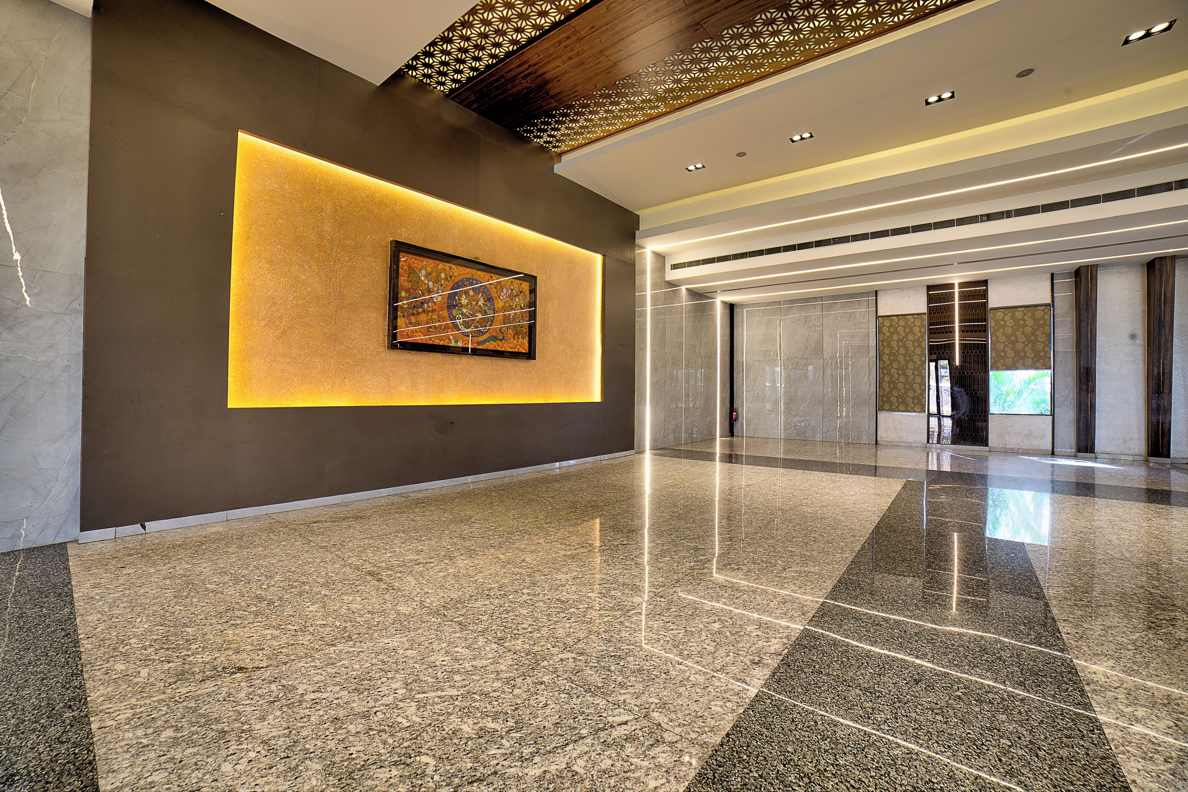 A spacious lobby with a polished granite floor, a modern ceiling design, and a framed artwork on the wall.
