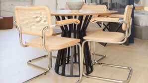 A modern dining area with a round table and six chairs with metal frames and woven seats. - Liiiving in Porto - Modern Coastline Apartment (Porto)