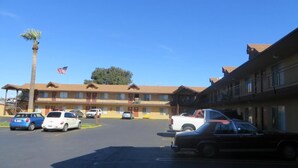 A motel with multiple rooms, a parking lot, and an American flag. - HOTEL SALINA (Beaumont)