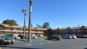 A parking lot with several cars, a building with multiple balconies, and a clear blue sky. - HOTEL SALINA (Beaumont)