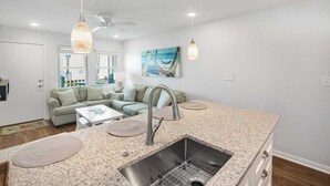 A modern kitchen with granite countertops, a stainless steel sink, and pendant lighting.