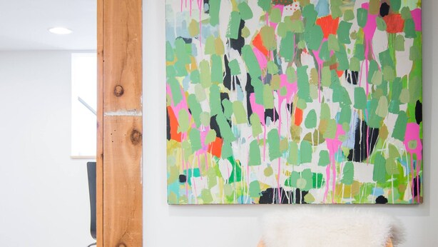 A room with a wooden floor, a white fluffy chair, a colorful abstract painting on the wall, and a wooden column. - Renovated basement studio in historic Mapleton Hill. (Boulder)