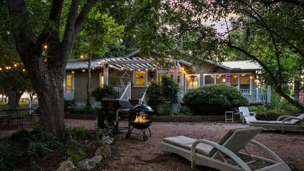 Un patio exterior acogedor con una parrilla, sillones de descanso y una casa con porche cubierto.