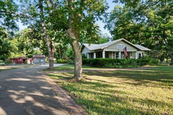 A single-story house with a gabled roof, surrounded by a well-maintained lawn and trees.