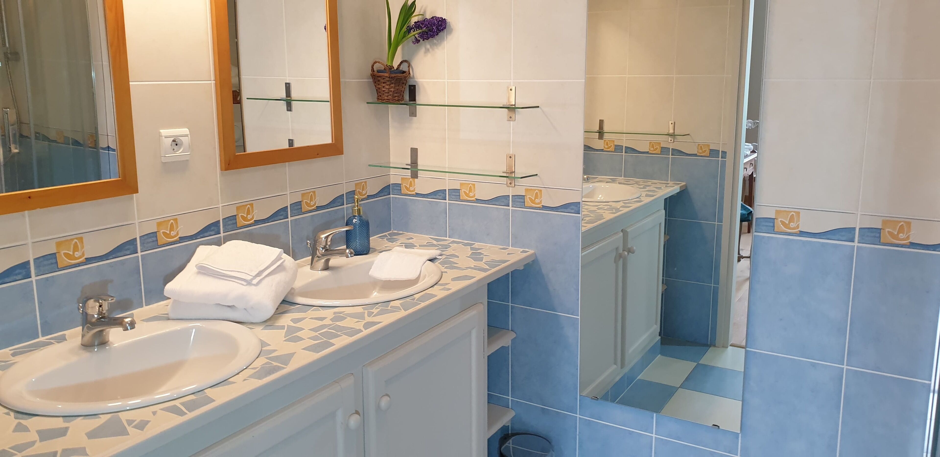 A bathroom with two sinks, a mirror, and a shower.