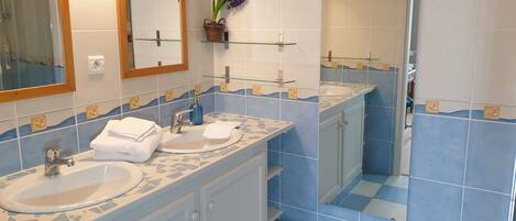 Un baño con dos lavamanos, un espejo y una ducha.