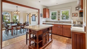 A kitchen with wooden cabinets, a central island, and a dining area with chairs.