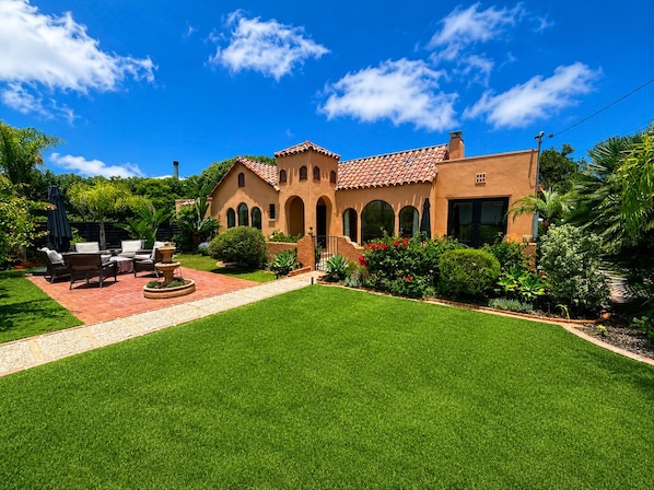 A house with a patio, outdoor furniture, and a well-maintained lawn.