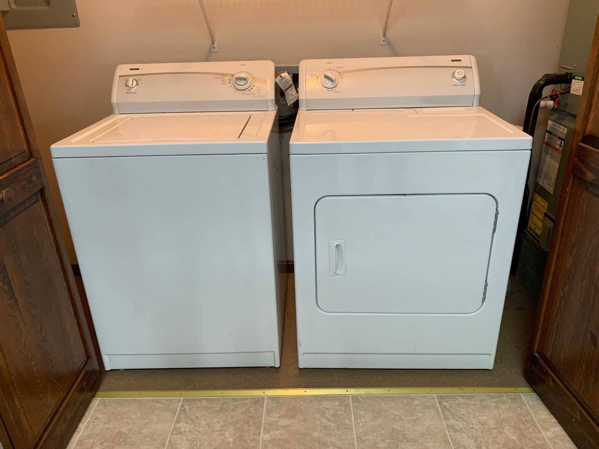Une buanderie équipée de deux machines à laver à chargement frontal blanches et d’un sèche-linge.