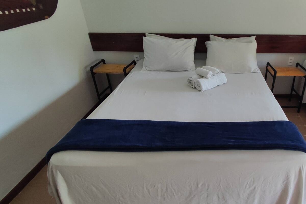 A hotel room with a large bed, two bedside tables, and a window.