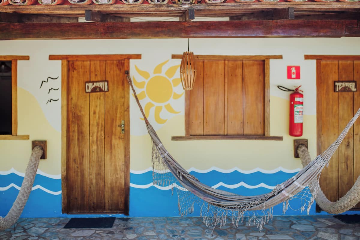 A wooden door with a sign, a hammock, and a fire extinguisher on the wall.
