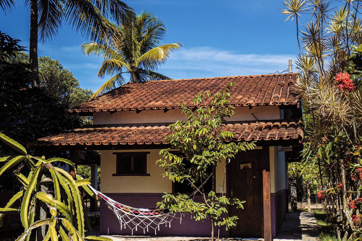 A house with a tiled roof, a small porch, and a hammock.