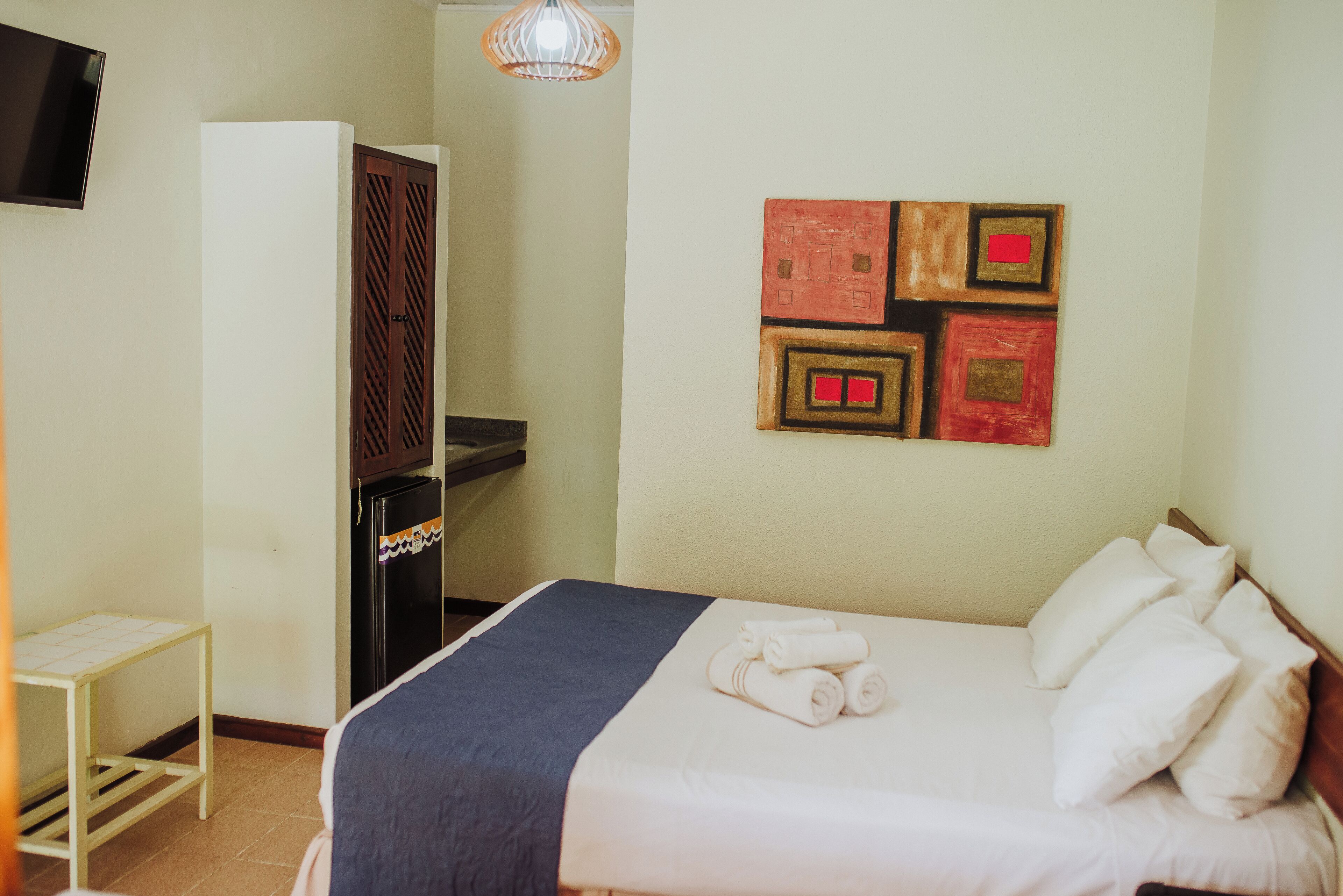 Une chambre d’hôtel équipée d’un lit, d’un bureau, d’une armoire et d’un mur décoré d’œuvres d’art.