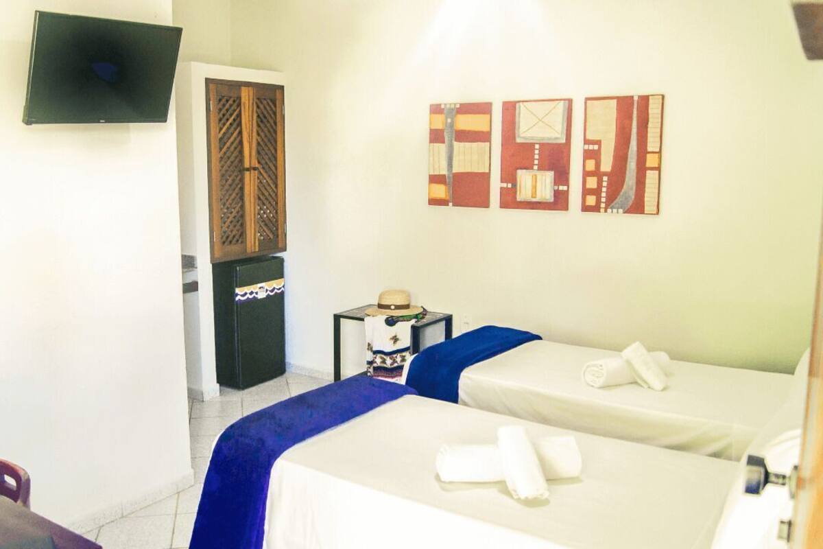 A hotel room with two beds, a TV, a desk, and wall art.
