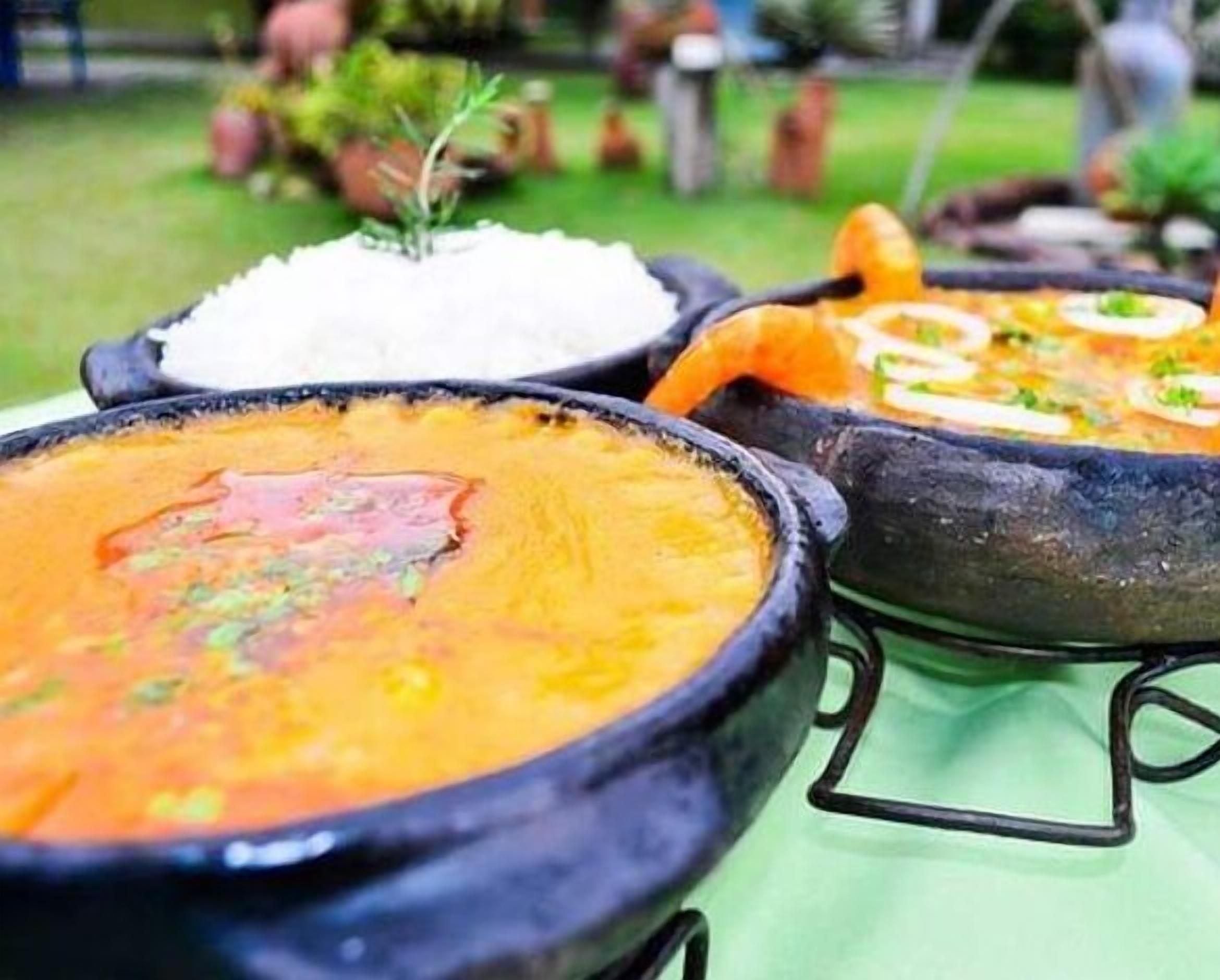 A close-up of three large ceramic pots with different colored soups, placed on a table outdoors.