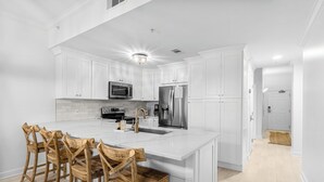 A modern kitchen with white cabinetry, a central island, and bar stools.