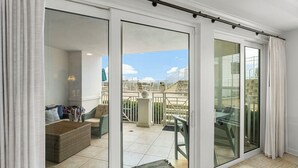 A spacious balcony with a sliding glass door, a wicker sofa, and a small table.