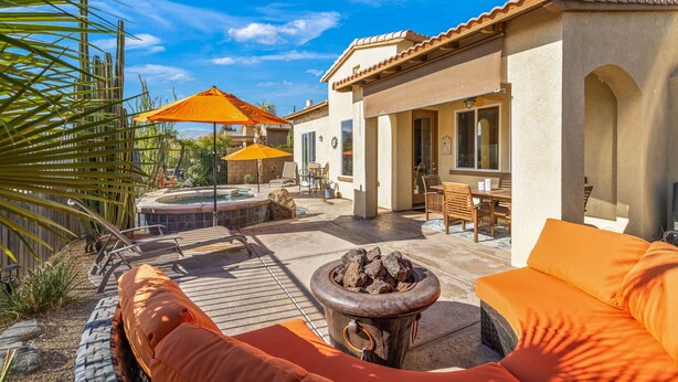 A patio with outdoor furniture, a fire pit, and a hot tub.