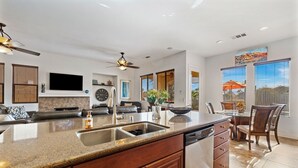 A modern kitchen with granite countertops, a dishwasher, and a dining area with a table and chairs.