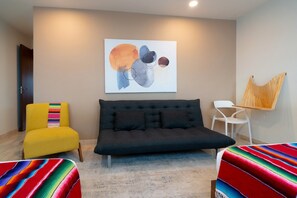 Una sala de estar moderna con un sofá, un sillón colorido y un cuadro en la pared.