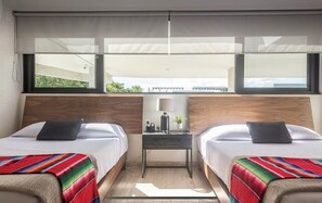 Une chambre d’hôtel avec deux lits, une table de chevet, une lampe et une vue sur la verdure.