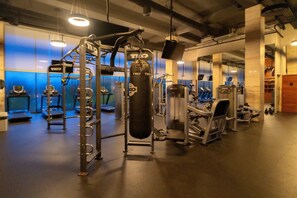 Een sportschool met diverse fitnessapparatuur, waaronder een squatrek, een bokszak en cardio-apparaten.