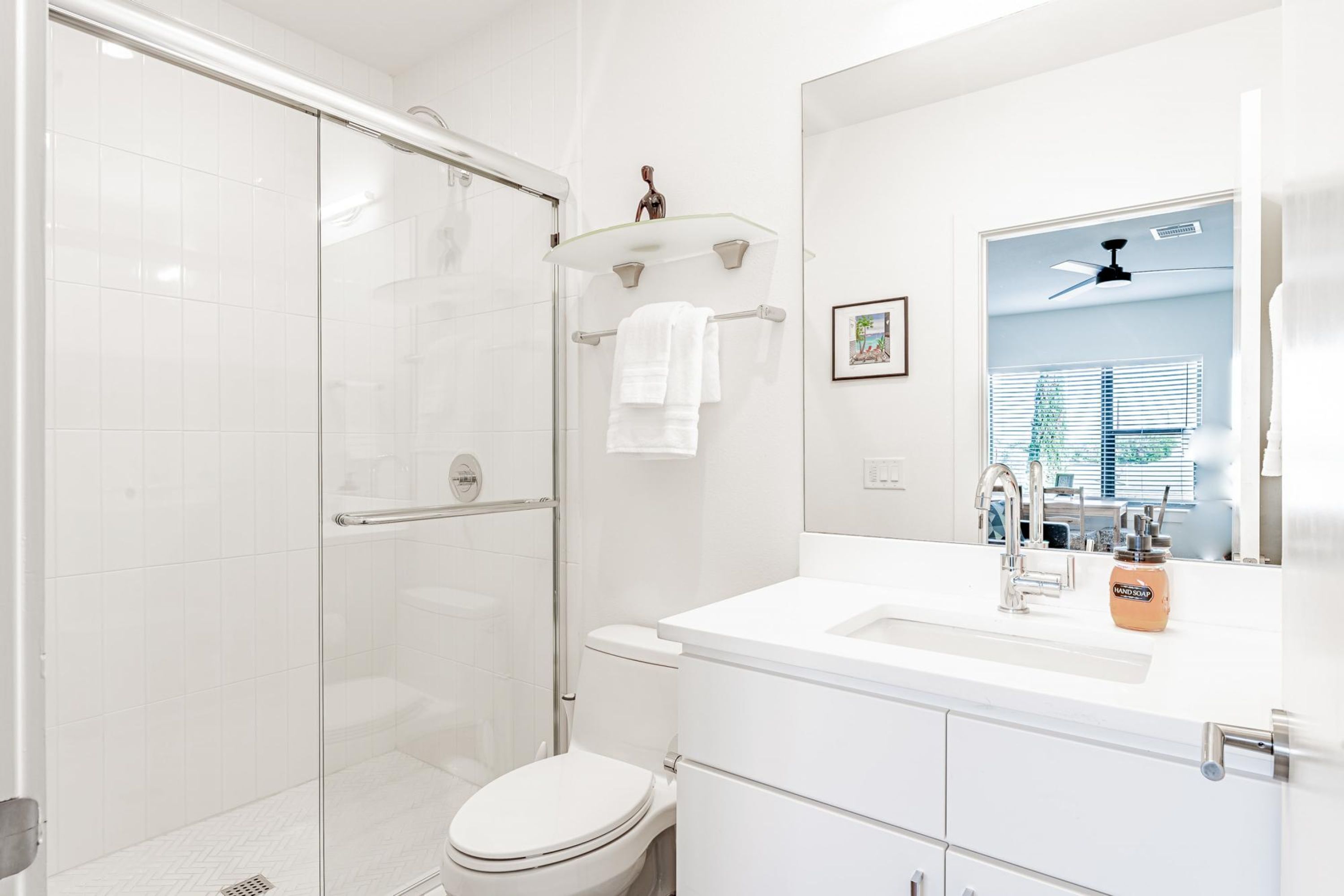 Un bagno moderno con cabina doccia in vetro, un water bianco e un mobile lavabo con specchio.