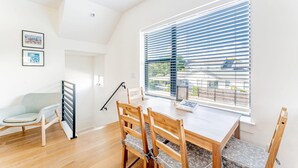 A modern dining area with a wooden table and chairs, a window with blinds, and a view of the outside. - East Downtown 3BR Condo w Fast Wifi and Sleeps 8 (Austin)