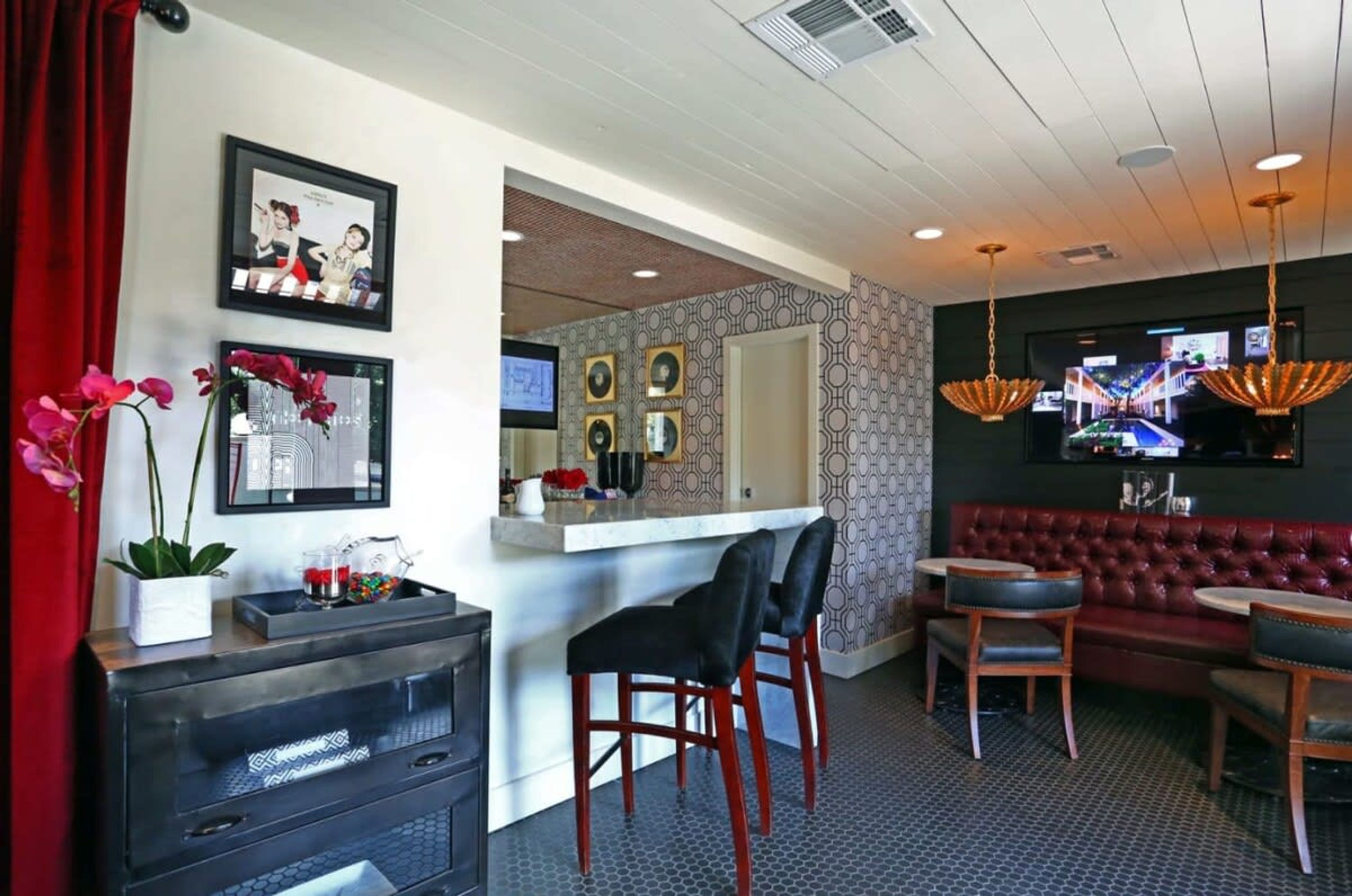 A bar area with a counter, stools, and a red upholstered sofa.