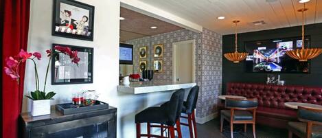 A bar area with a counter, stools, and a red upholstered sofa.