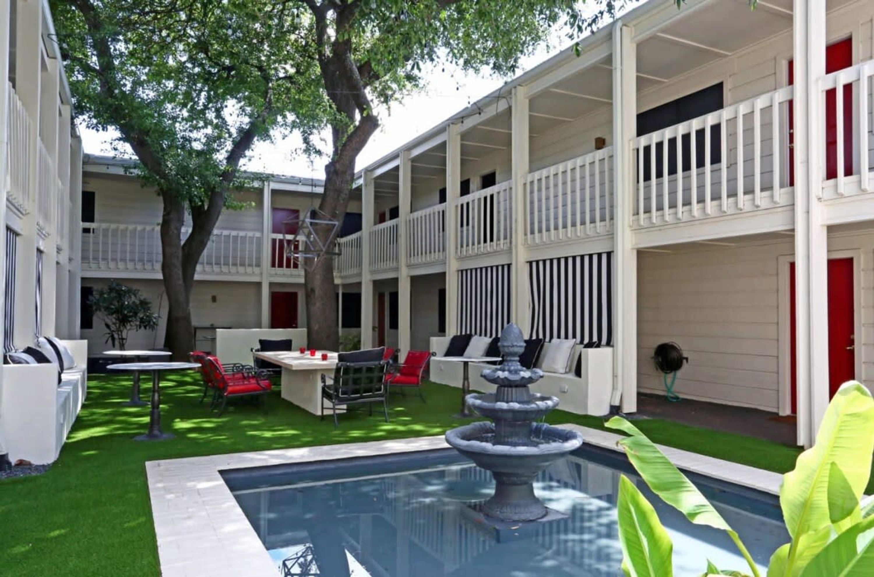 Un patio con piscina, mobiliario exterior y una fuente.