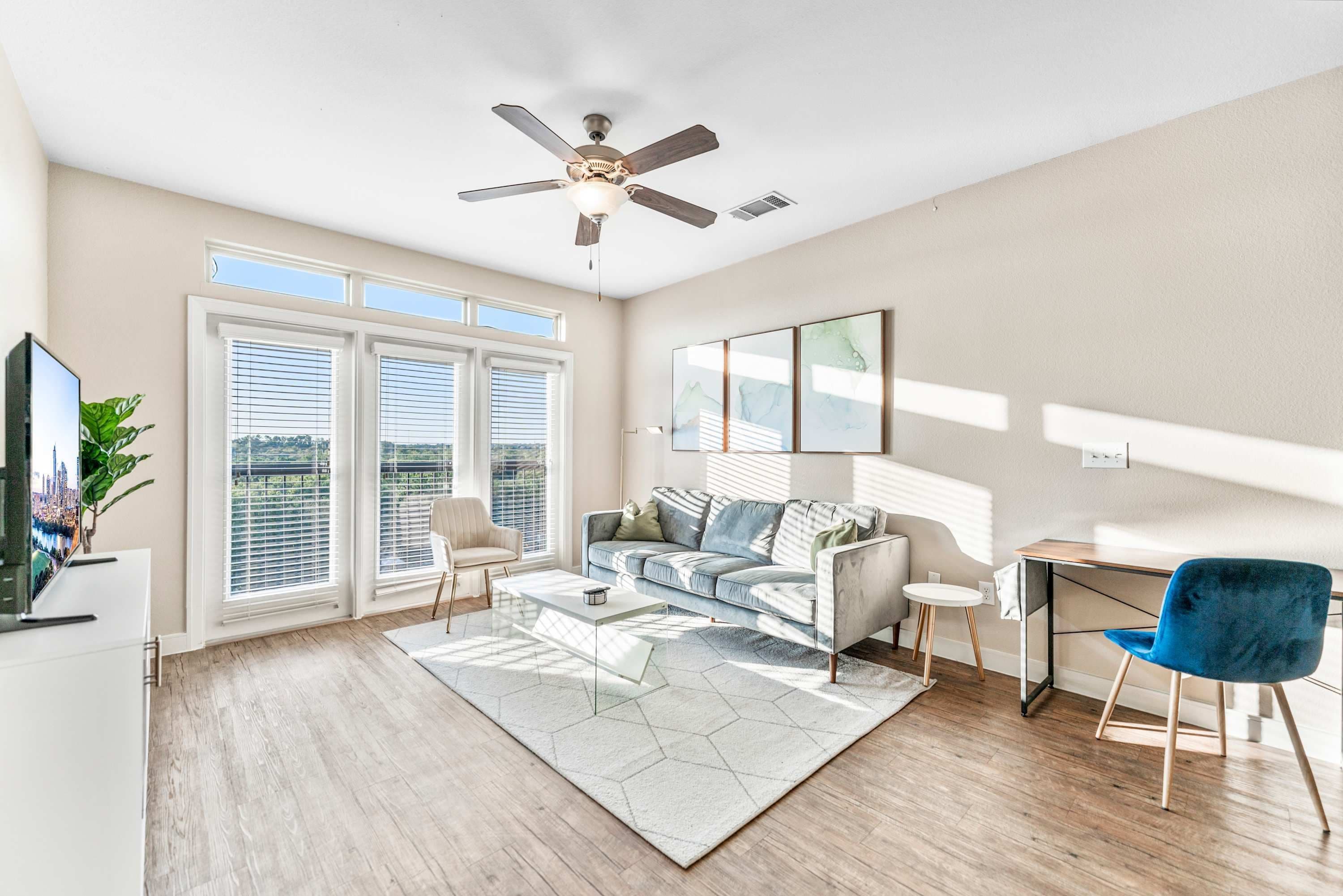 A modern living room with a sofa, a coffee table, a TV, and a ceiling fan.
