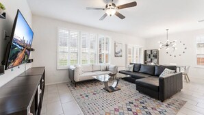A modern living room with a flat-screen TV, two sofas, a coffee table, and a ceiling fan.