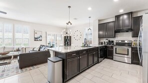A modern kitchen with dark cabinets, stainless steel appliances, and a central island. - Cozy 4BR House Close to Cota DT w Fast Wifi (Austin)