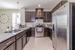 A modern kitchen with dark wood cabinets, stainless steel appliances, and a granite countertop.