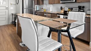 Eine moderne Küche mit Edelstahlgeräten, Holzschränken und einem Glastisch mit weißen Stühlen.