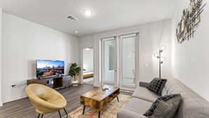 A modern living room with a sofa, a coffee table, a TV, and a decorative wall piece.