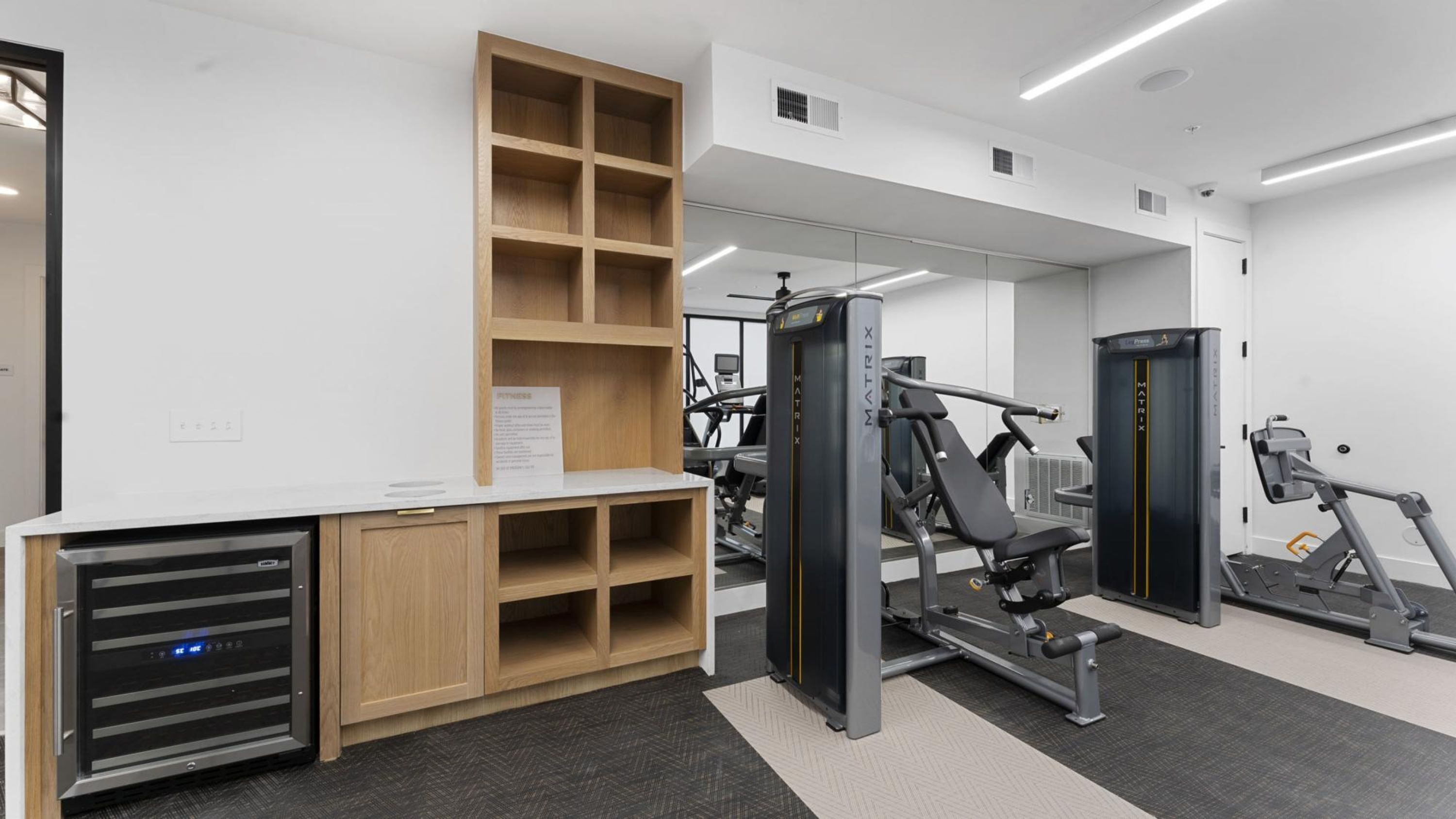 Un gimnasio moderno con equipo de ejercicio, un armario de madera y un espejo.