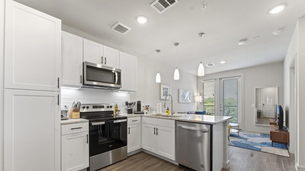 A modern kitchen with white cabinets, stainless steel appliances, and a central island. - Prime Soco Cozy 1BR King Suite w Pool Parking (Austin)