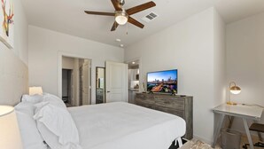 A bedroom with a bed, a ceiling fan, a TV on a wooden dresser, and a desk with a lamp. - Prime Soco Cozy 1BR King Suite w Pool Parking (Austin)