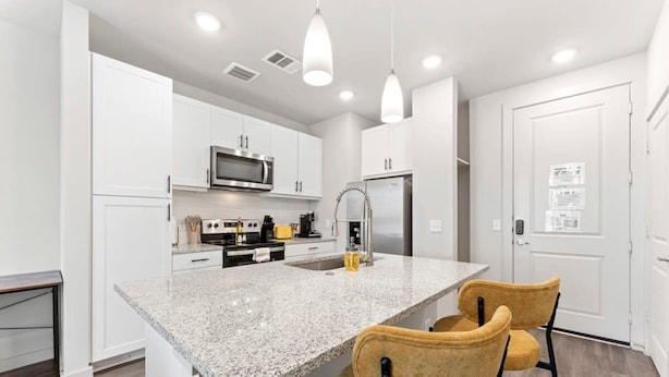 A modern kitchen with white cabinets, a granite countertop, stainless steel appliances, and pendant lighting. - Prime Soco Quaint 1BR King Suite w Pool Parking (Austin)