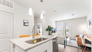 A modern kitchen with a granite countertop, stainless steel appliances, and pendant lighting. - Prime Soco Quaint 1BR King Suite w Pool Parking (Austin)