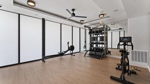 A spacious room with a ceiling fan, exercise equipment, and a large mirror reflecting the room. - Prime Soco Airy 1BR King Suite w Pool Parking (Austin)