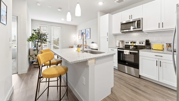 A modern kitchen with white cabinets, stainless steel appliances, and a central island with bar stools.